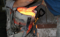 Pouring molten metal into sand cast mold made with FDM.
